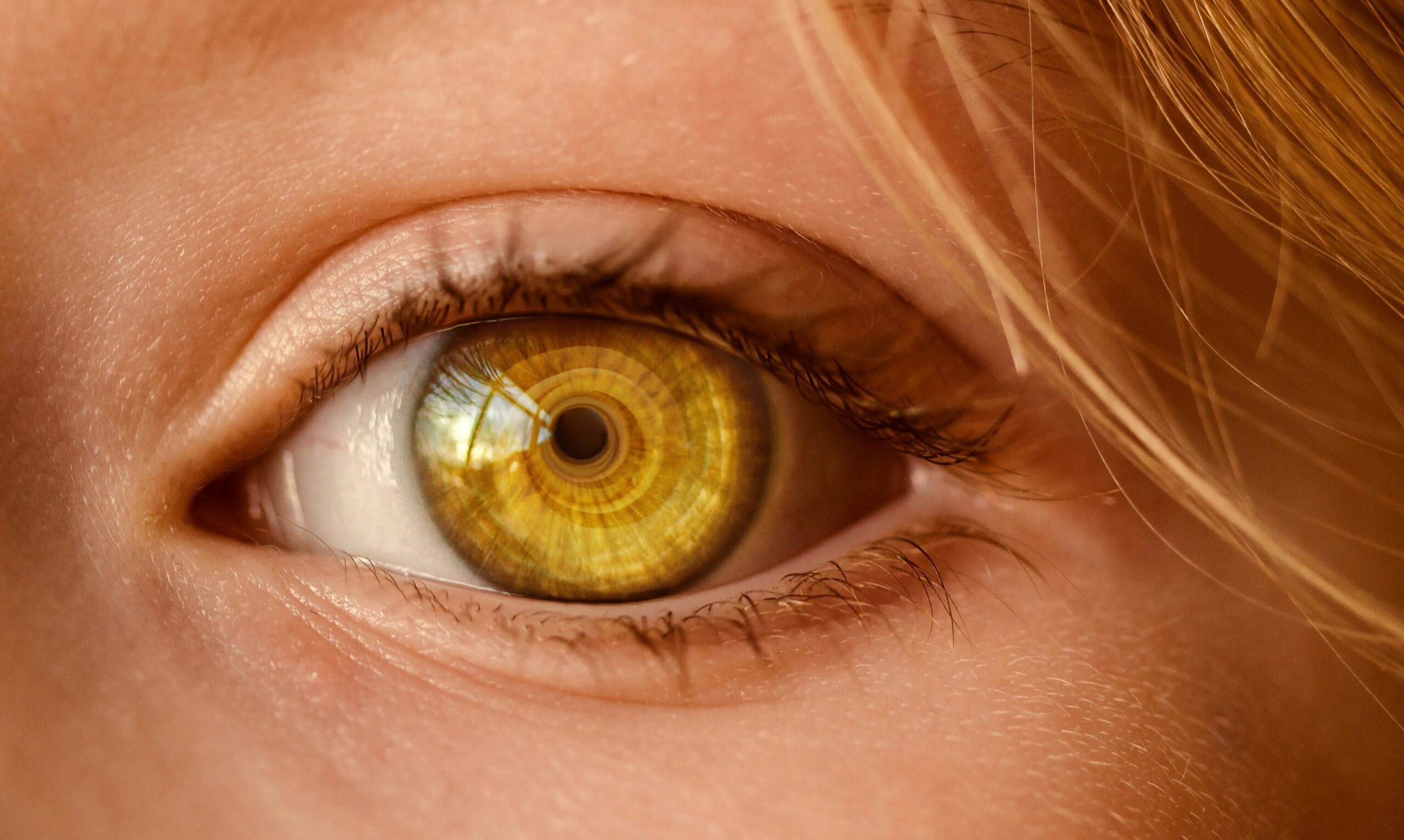 Detailed close-up of a human eye with a unique golden iris and spiral light reflection.